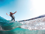 Person standing on a wave with clear blue water and sky