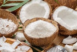 Coconut halves and pieces on a wooden surface with a grater.
