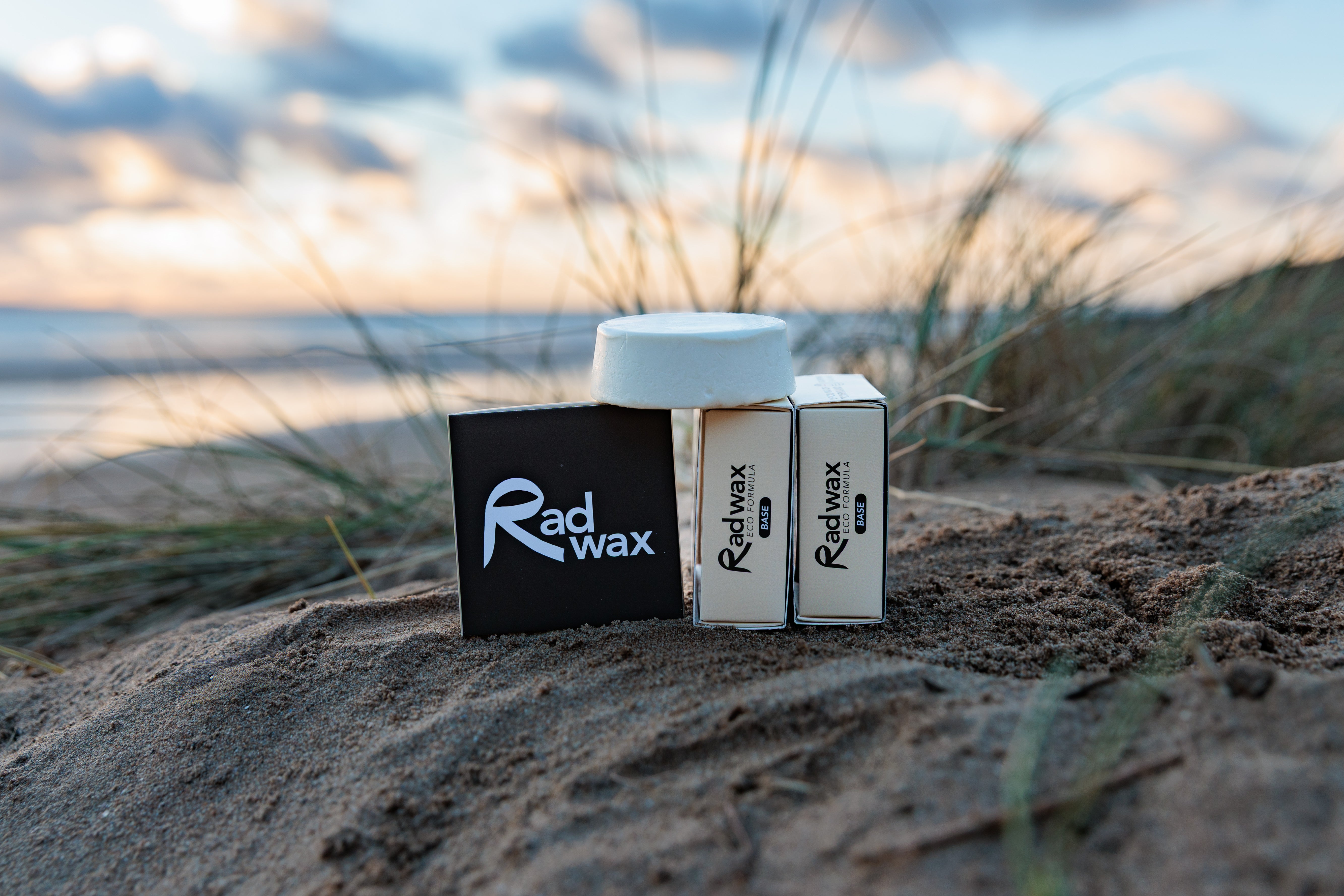 Rad Wax Base Coat products on sand with beach background