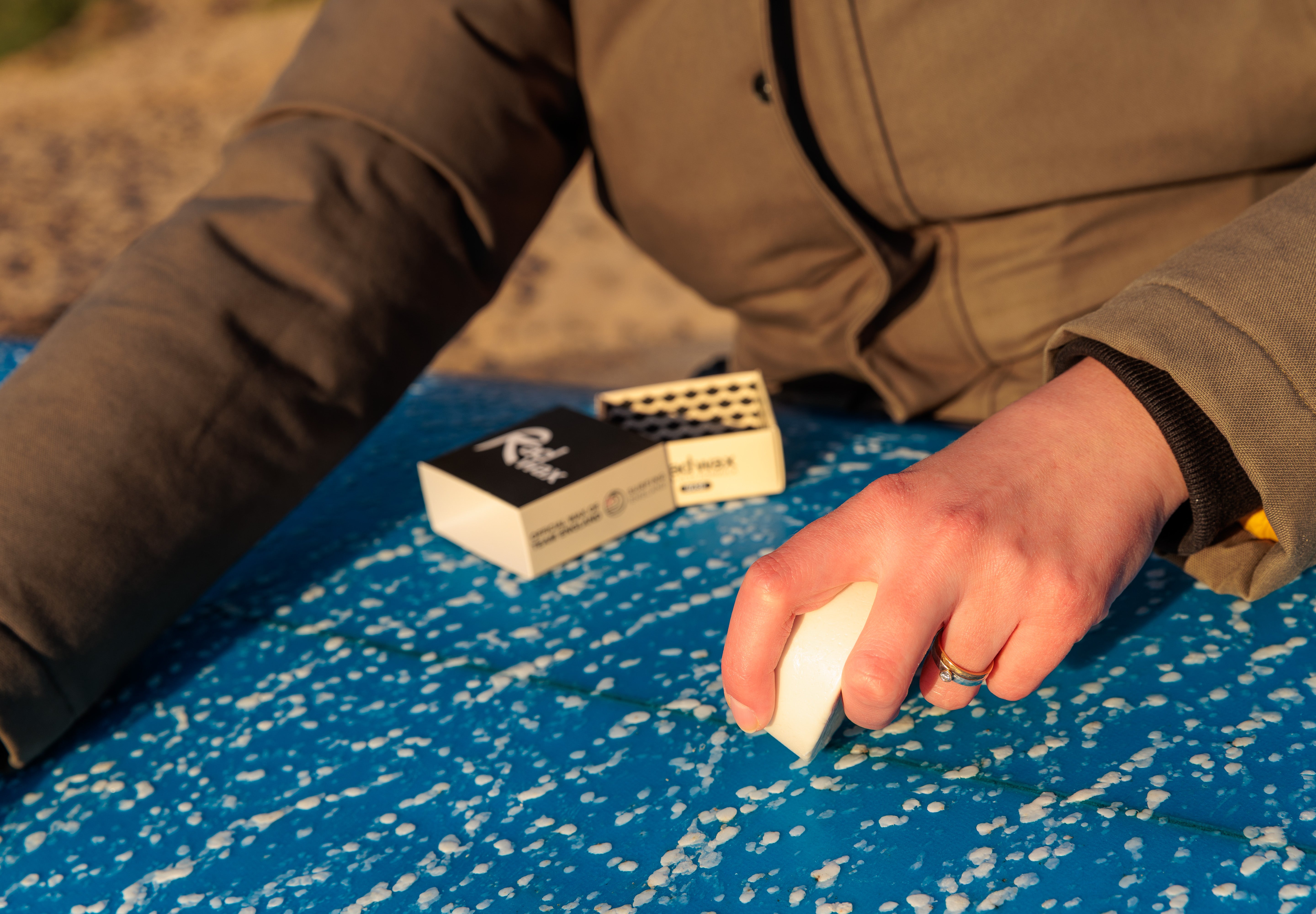 Surfer waxing a board with Rad Wax Base Coat