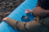 Surfer applying a Rad Wax to a surfboard